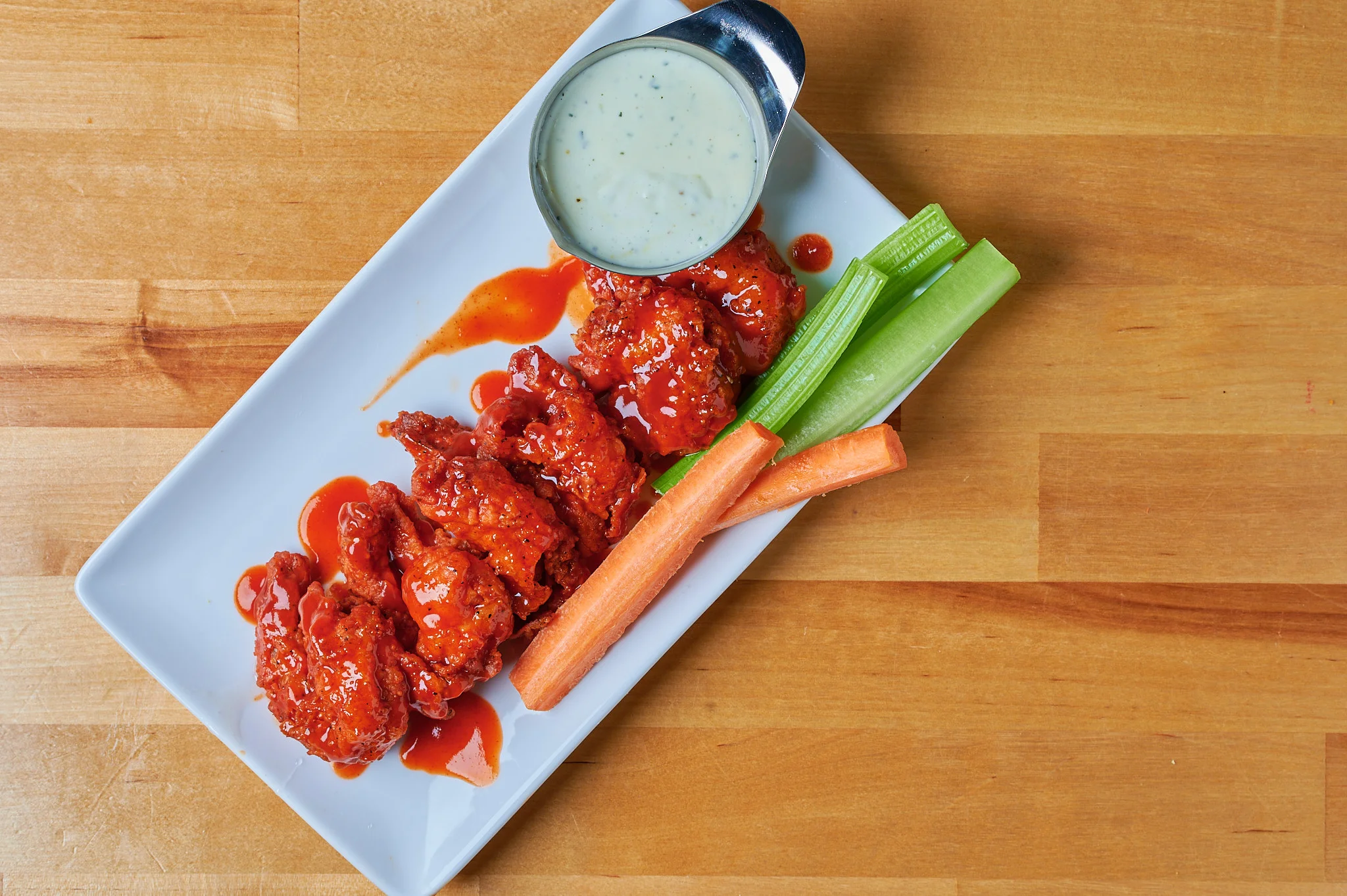 Top-Down View of Boneless Wings: A captivating bird's-eye view of these succulent, bite-sized chicken pieces, expertly breaded and fried to a crispy perfection, alongside a selection of enticing dipping sauces. 🍗👀