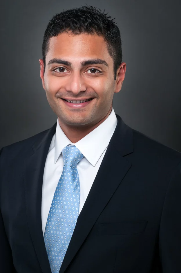 Close-up professional headshot portrait in a well-lit studio, featuring a confident individual with a friendly smile and crisp attire.
