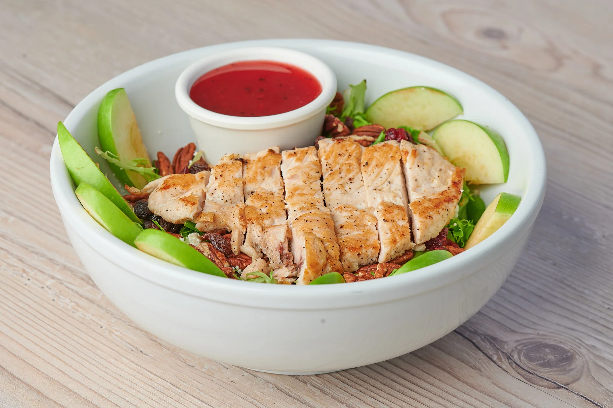 Delicious Chicken Apple Pecan Salad: A combination of grilled chicken breast, Granny Smith apple slices, candied pecans, dried cranberries, raisins, crumbled feta cheese, all perfectly complemented by a fat-free raspberry vinaigrette dressing.