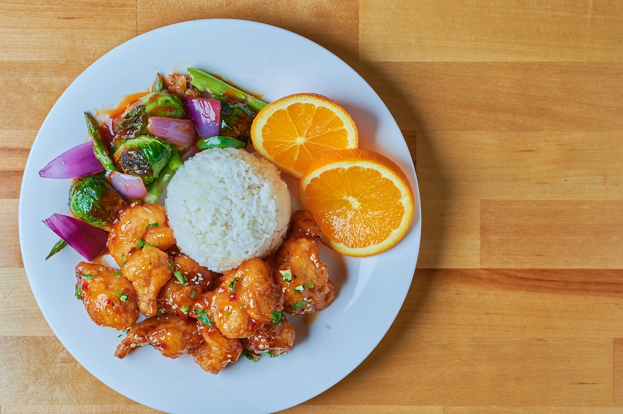 Orange Chicken: A delicious dish featuring crispy chicken pieces coated in a tangy and sweet orange sauce, garnished with fresh orange zest.